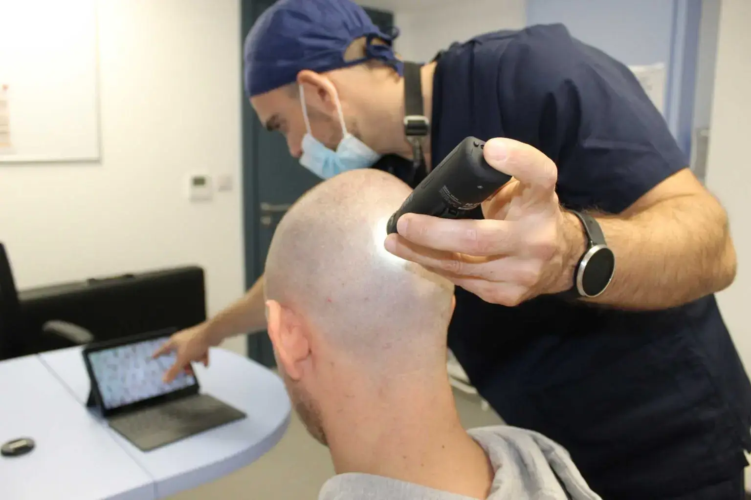 Dr Bonaros assessing a patient's scalp with a handheld trichoscopy camera