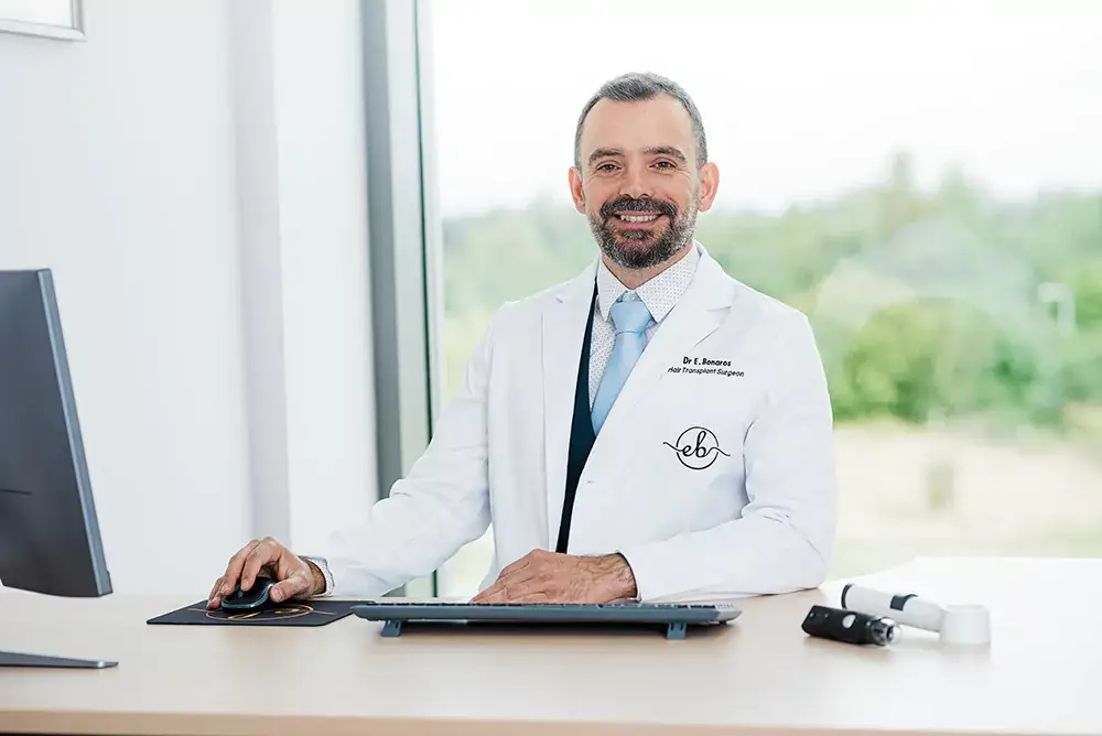 Dr Epameinondas Bonaros at his desk during a hair loss consultation
