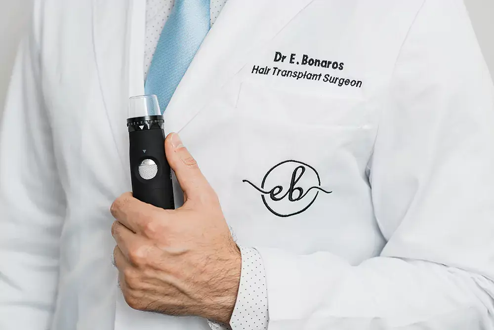 Dr Bonaros in a clinic coat holding a trichoscopy device
