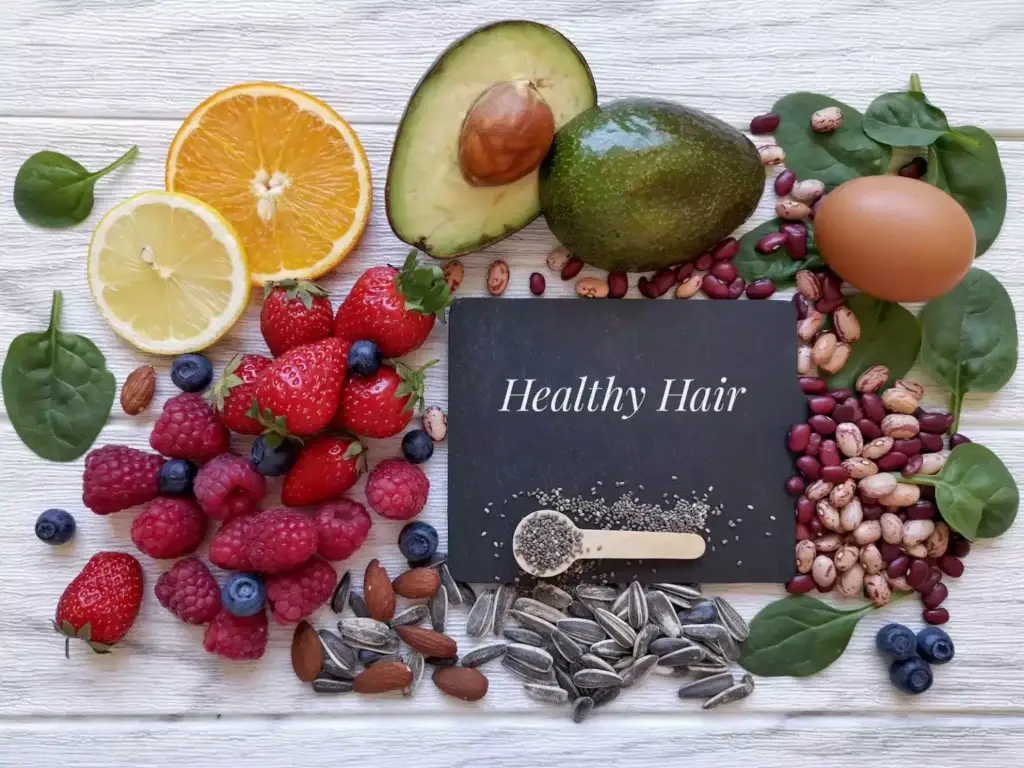 Fresh fruit, nuts and vegetables arranged around a healthy hair notebook